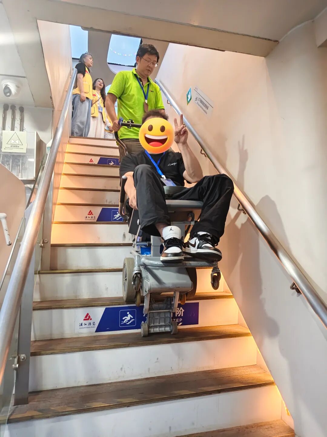展大工作人员操作爬楼机协助残友登船